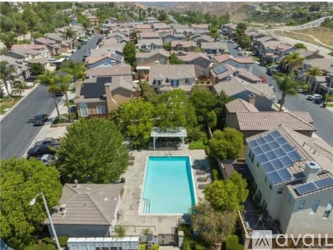 A bird's eye view of a neighborhood with a swimming pool and solar panels on the roofs.