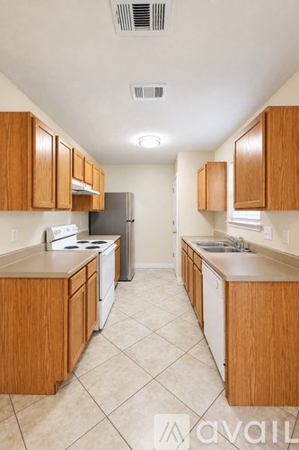 A kitchen with wooden cabinets and a tiled floor.