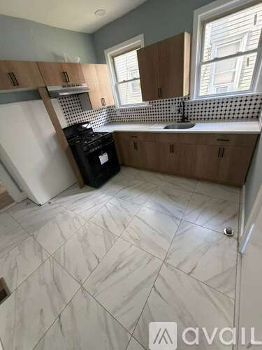 A kitchen with a black stove top oven and a white tiled floor.