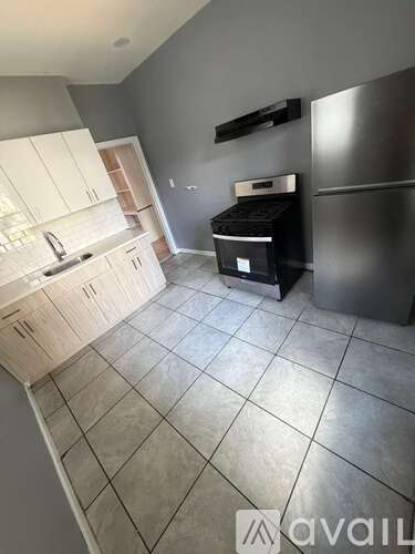 A kitchen with a stainless steel refrigerator and a black stove top oven.