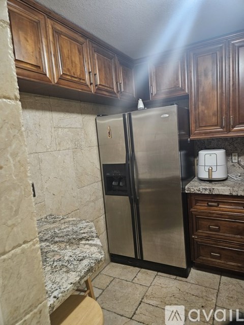 A kitchen with a stainless steel refrigerator and a marble countertop.