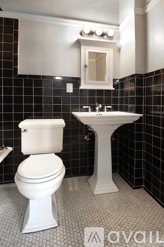 A white toilet and sink in a black and white tiled bathroom.