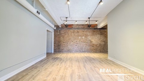 A room with a wooden floor and a brick wall.
