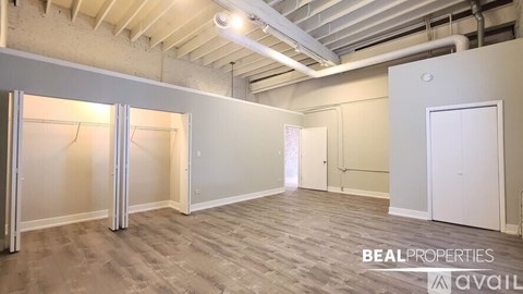 A spacious room with a slanted ceiling and a large window on the left side.