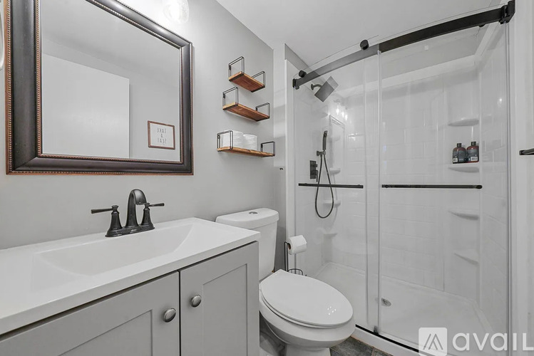 A bathroom with a white toilet, sink, and shower.