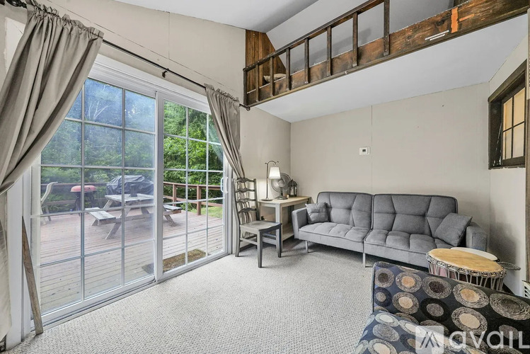 A living room with a grey sofa and a glass door leading to a patio.