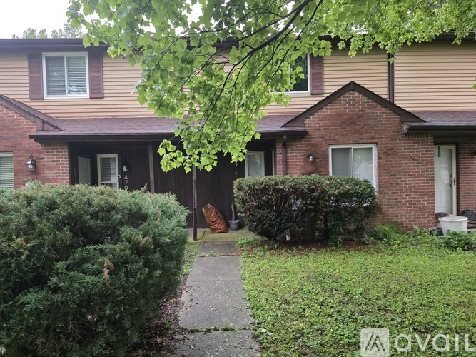 A house with a brown roof and a tree in front.