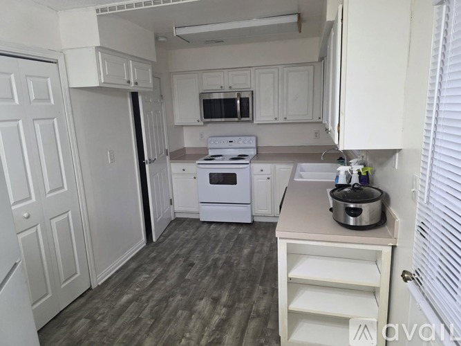 A kitchen with white cabinets and a grey floor.