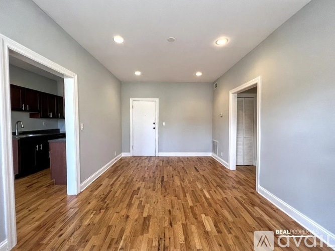 A spacious room with wooden flooring and white walls.