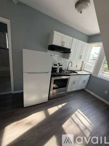 A kitchen with white appliances and wooden floors.
