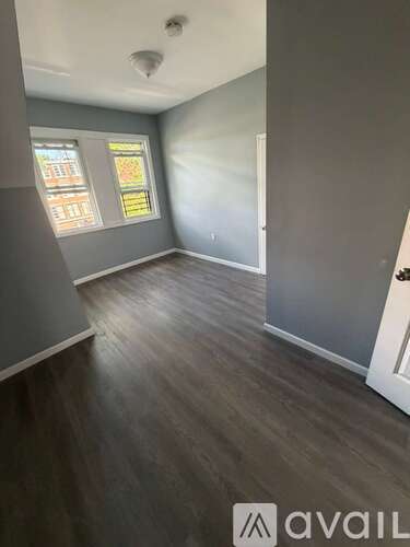A room with grey walls and wooden flooring with a white door.