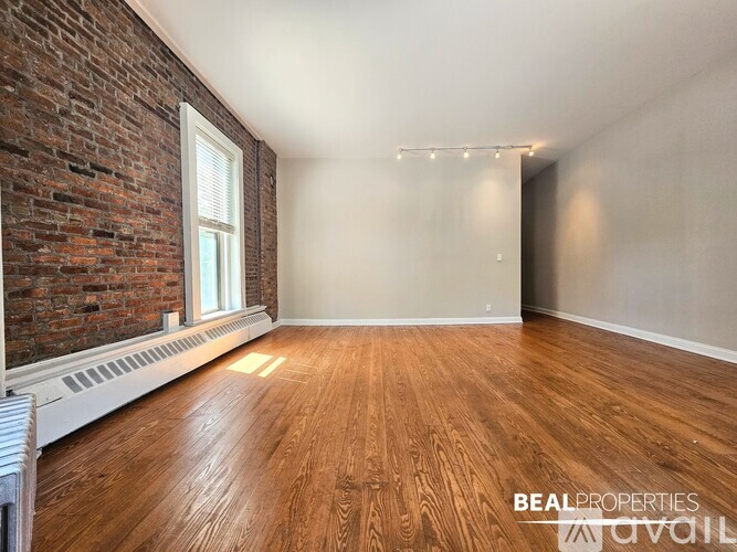 A room with wooden floors and a brick wall.