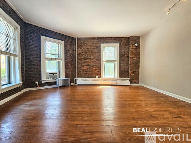A spacious room with wooden floors and brick walls.