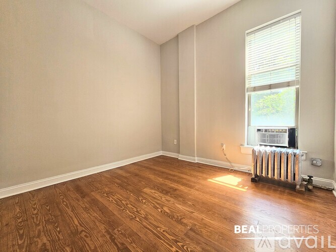 A room with wooden flooring and a window showing a view of a building outside.