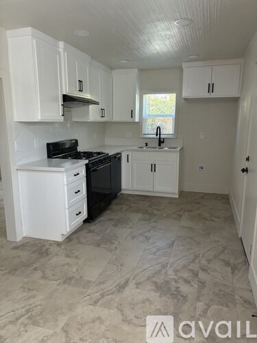 A kitchen with white cabinets and a black stove top oven.