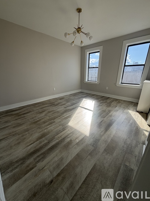 A room with wooden flooring and a chandelier.