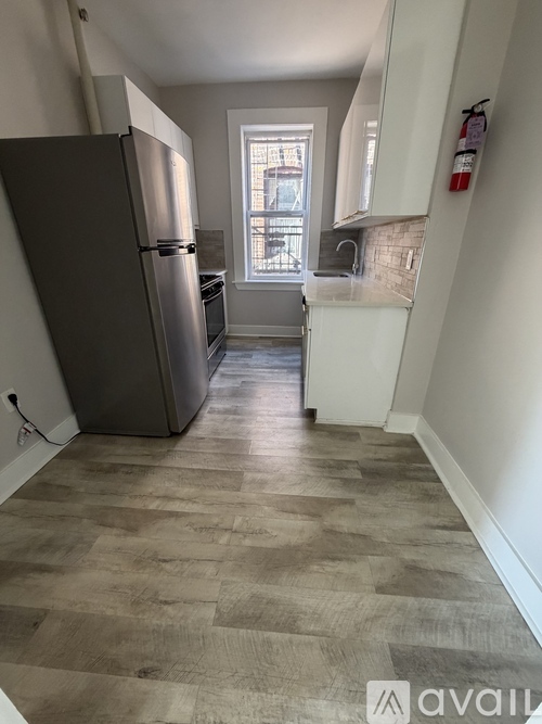 A kitchen with a refrigerator and wooden flooring.