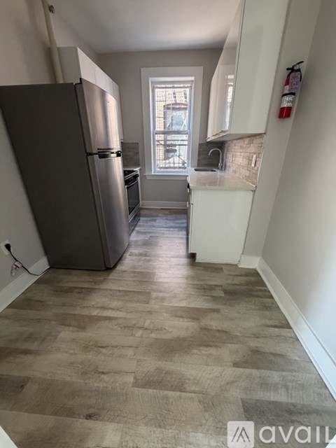 A kitchen with a refrigerator and wooden flooring.