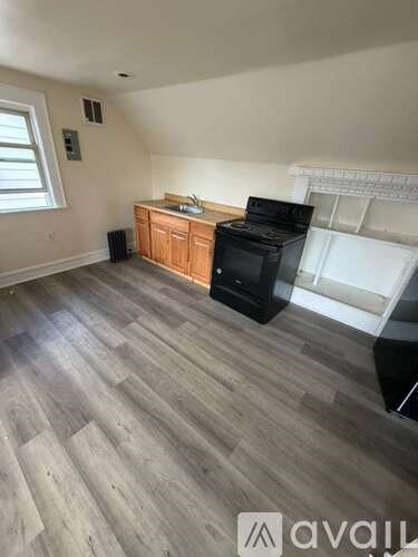 A kitchen area with a wooden cabinet, black microwave, and white fridge.