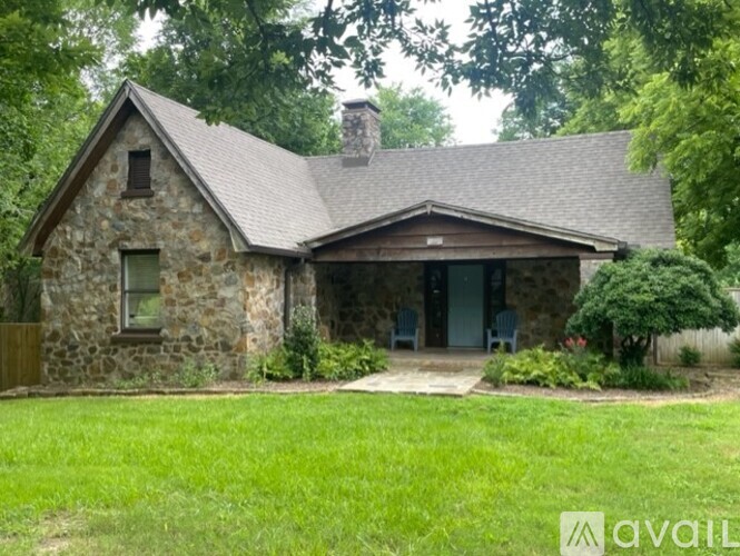 A stone house with a green lawn in front.