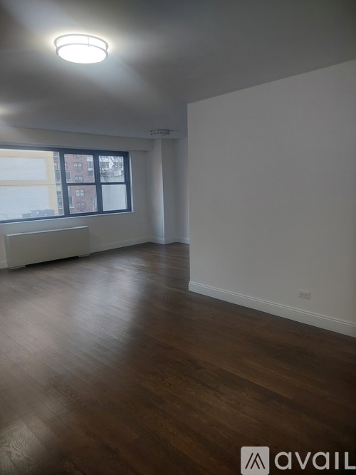 A room with wooden floors and a window overlooking a building.