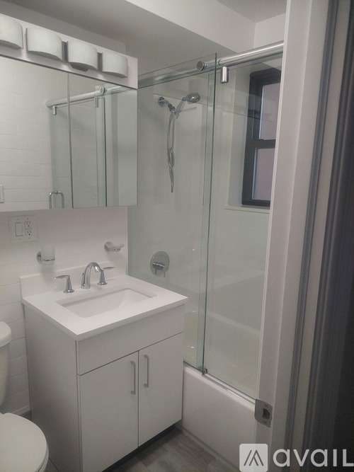 A white bathroom with a sink, toilet, and shower.