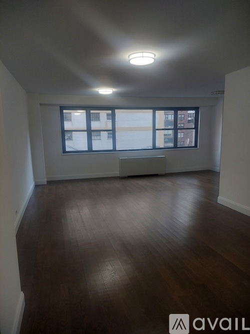 A room with wooden floors and a window overlooking a building.