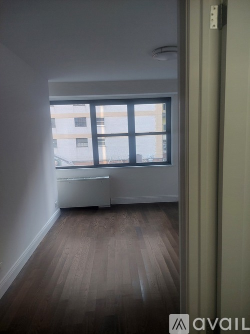 A room with wooden floors and a window overlooking a building.