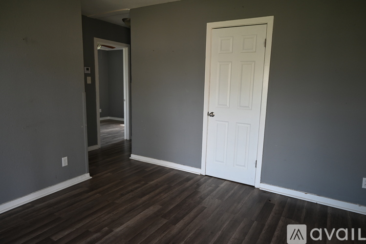 A room with a white door and a wooden floor.