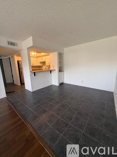 A large empty room with a kitchen in the background.