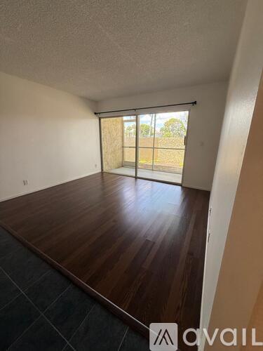 A room with wooden flooring and a sliding glass door leading outside.