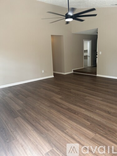 A room with a ceiling fan and wooden flooring.