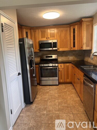 A kitchen with wooden cabinets and a black refrigerator.