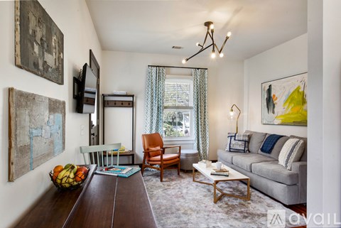A living room with a grey couch, a wooden table, and a painting on the wall.