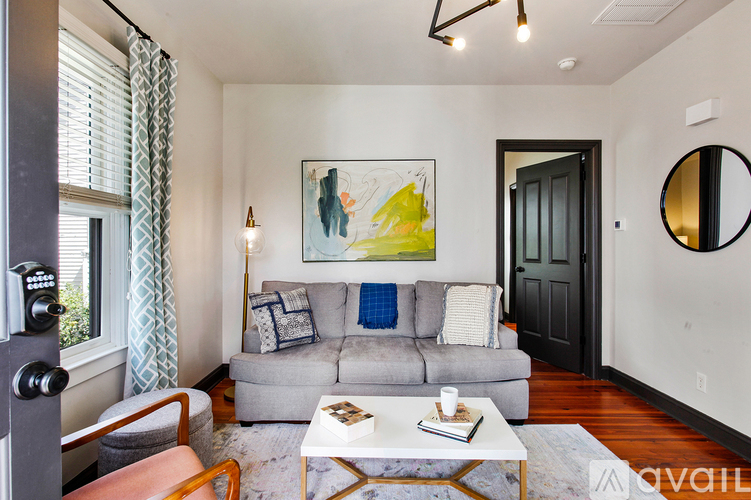 A living room with a grey couch, a coffee table, a painting on the wall, and a mirror on the wall.