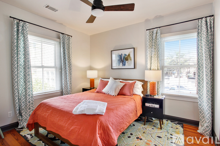 A bedroom with a bed, two lamps, and a ceiling fan.