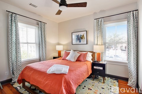 A bedroom with a bed, two lamps, and a ceiling fan.