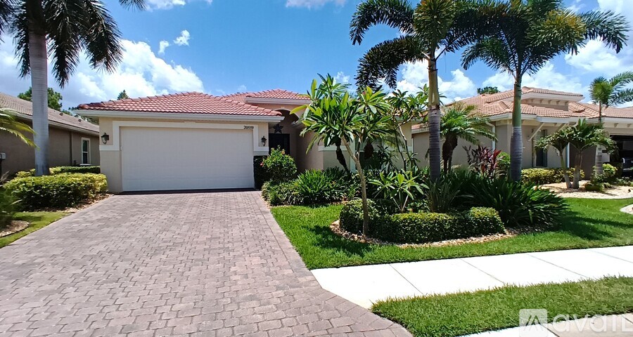 A house with a driveway and palm trees in front.