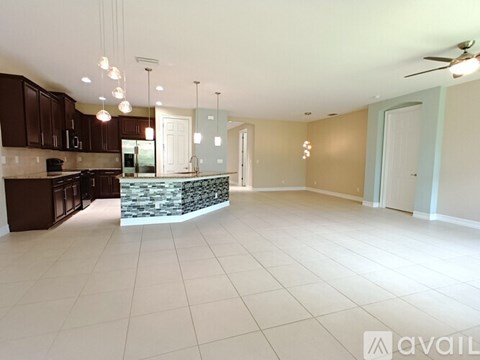 A spacious kitchen with dark brown cabinets and a stone countertop.