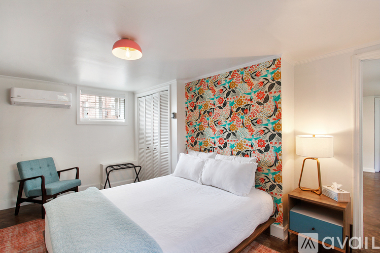 A bedroom with a floral wallpaper and a bed with white bedding.