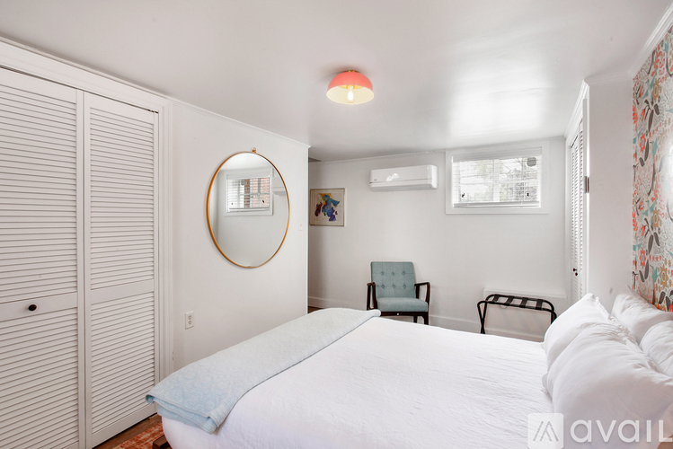 A bedroom with a large bed, a chair, and a mirror on the wall.