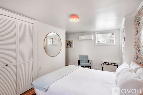 A bedroom with a large bed, a chair, and a mirror on the wall.
