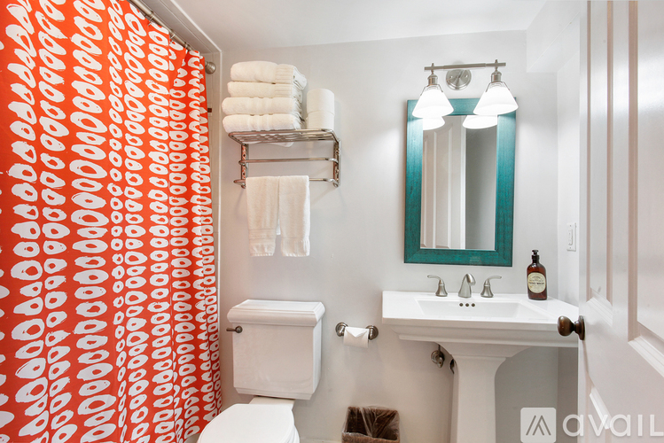 A bathroom with a toilet, sink, and a red and white shower curtain.