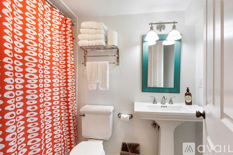 A bathroom with a toilet, sink, and a red and white shower curtain.