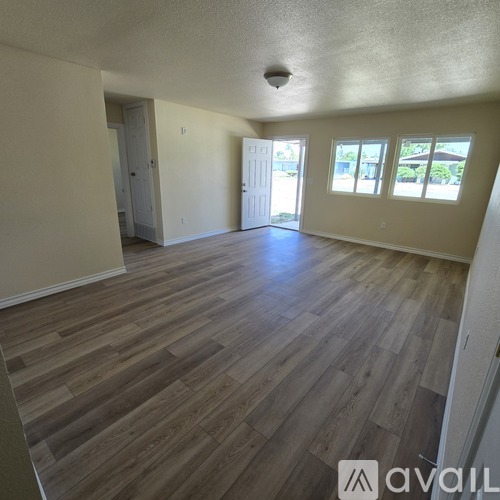 A spacious room with wooden flooring and two doors.