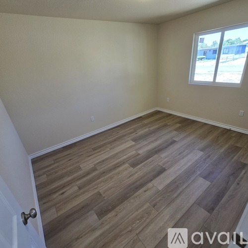 A room with wooden flooring and a window overlooking a parking lot.