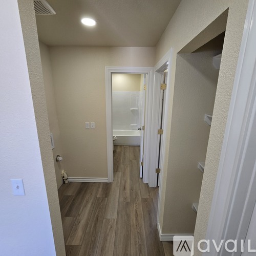 A hallway with wood flooring and white walls.