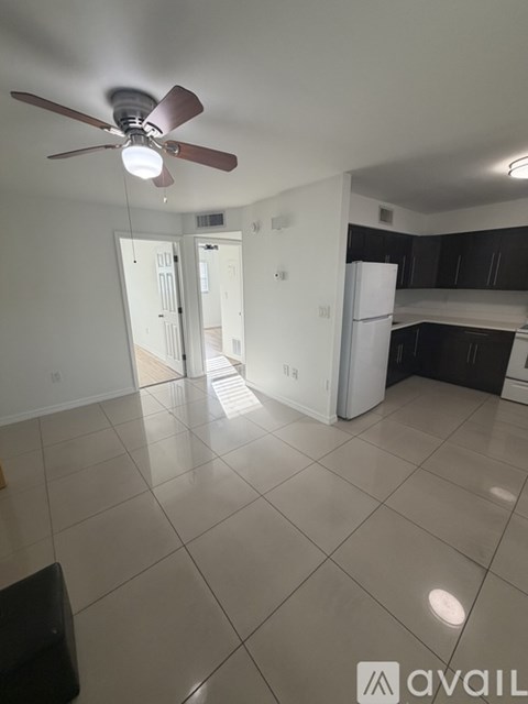 A kitchen with a white refrigerator and black cabinets.