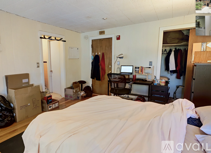 A bedroom with a bed, desk, and clothing rack.