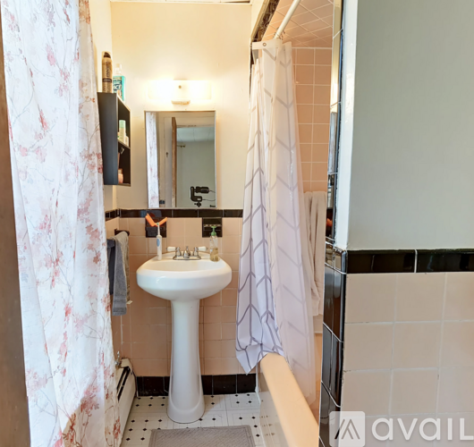A white pedestal sink in a bathroom with a floral shower curtain.